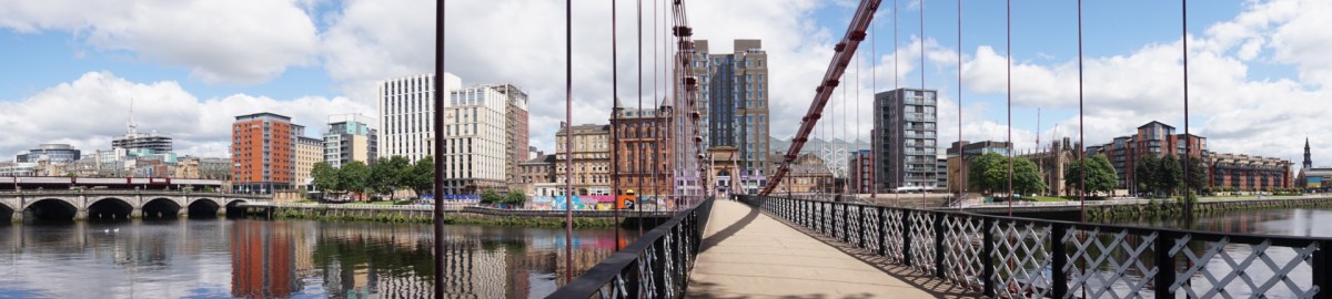 Panorama across a river from a bridge across with a view of tall buildings and street art