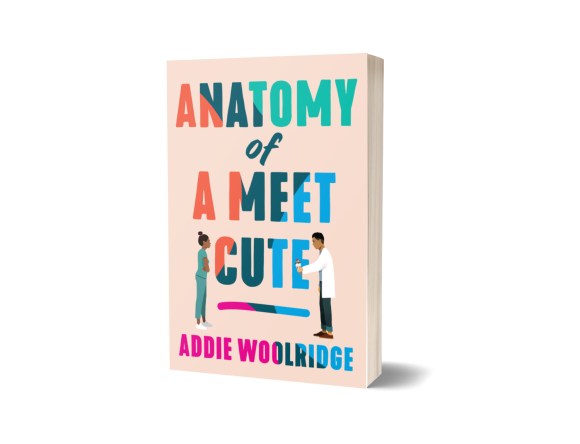 Cover of Anatomy of a meet cute. The background is a soft pink and the text is a tie-dye color with two people standing on the front. The woman is in green scrubs and has her arms crossed. The man is in a white coat and is holding an ice cream cone.